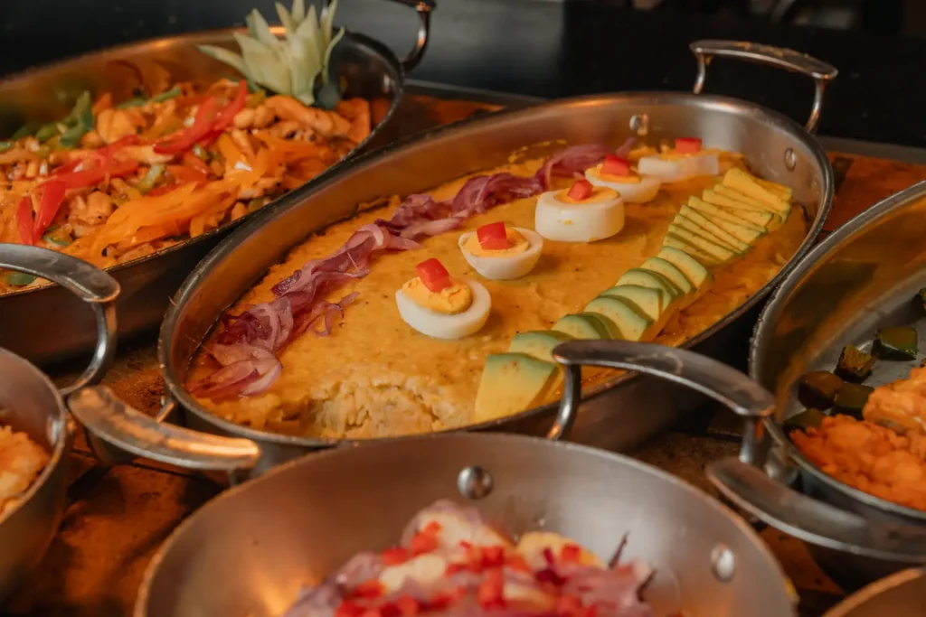 a table topped with lots of metal pans filled with food