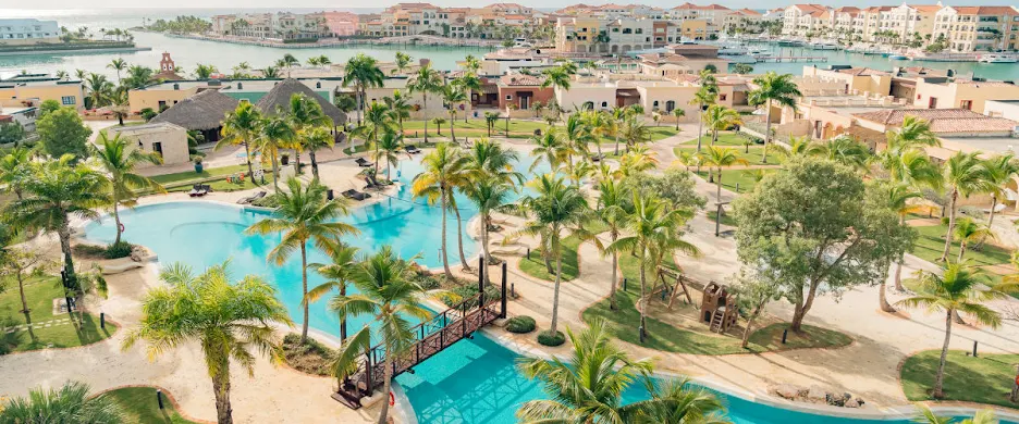 a large pool surrounded by palm trees next to a body of water